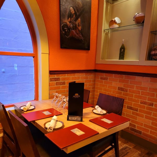 A reserved table at Namaste India Bistro, with vibrant orange walls and brick accents.